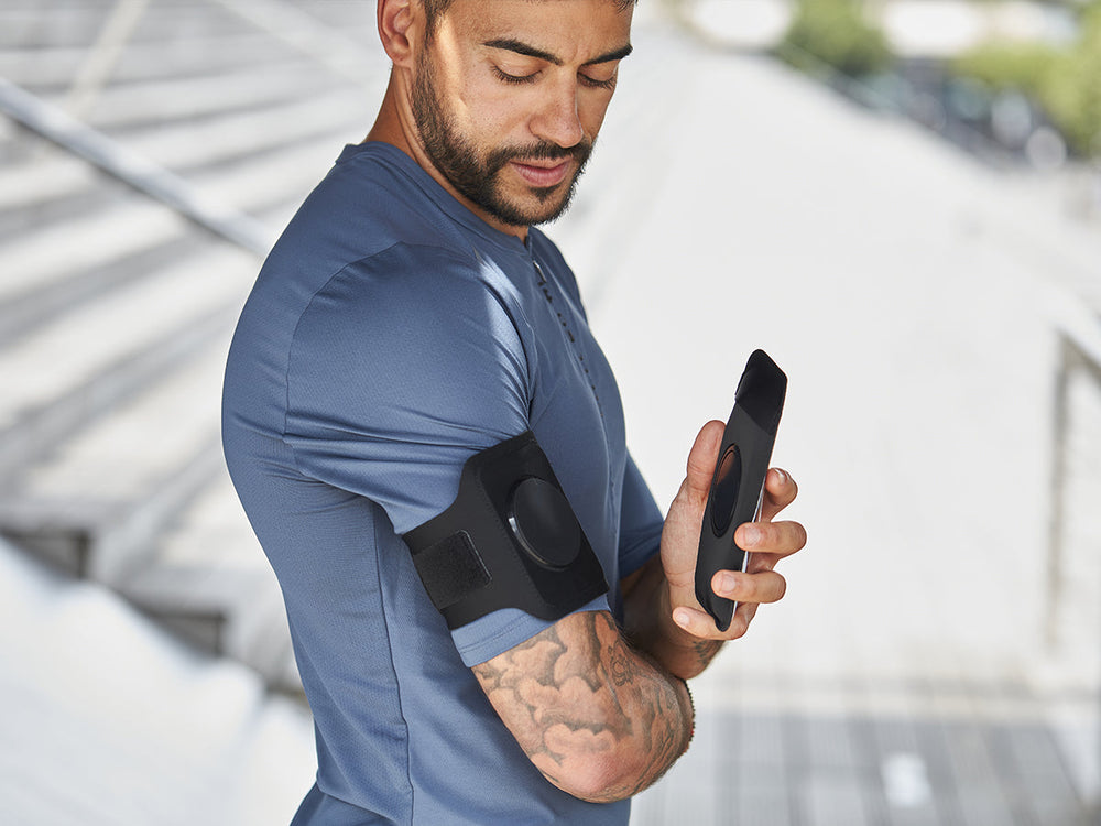 Homme utilisant le brassard Shapeheart, fixation magnétique sécurisée pour courir avec son smartphone.