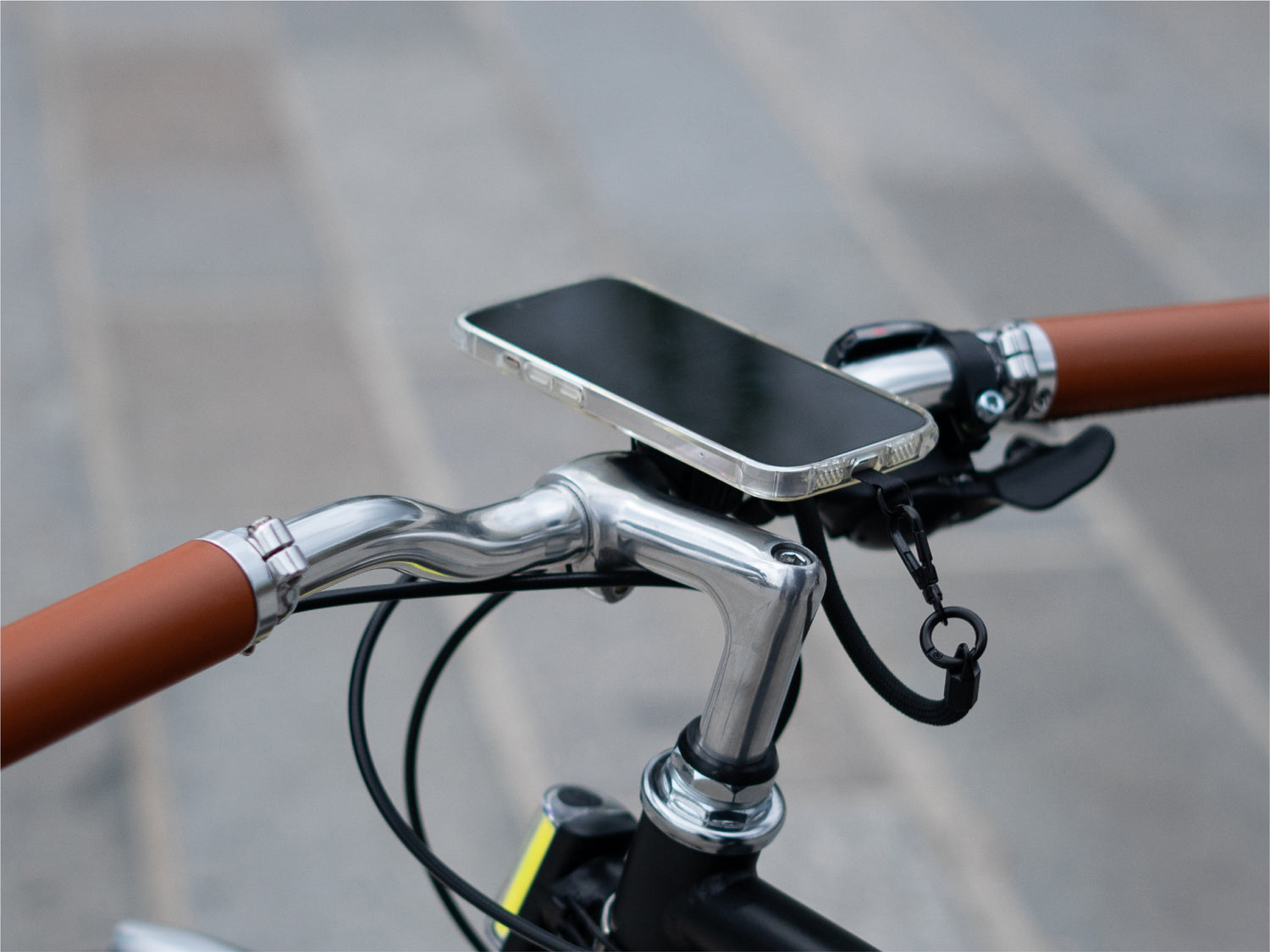 Smartphone fixé magnétiquement au support guidon, démontrant une installation minimaliste. Utilisation du cordon pour encore plus de sécurité
