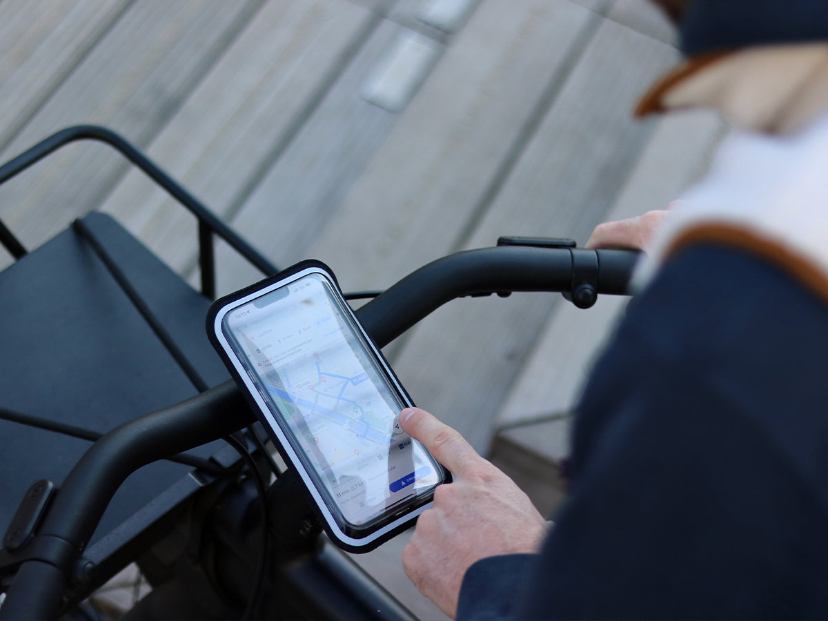 Vue du smartphone fixé sur le guidon du vélo dans sa pochette magnétique parfaitement tactile. Idéal pour la navigation en ville