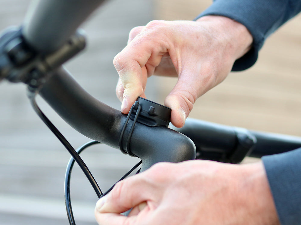 Fixation d’un support téléphone Shapeheart sur un guidon de vélo avec élastiques solides.